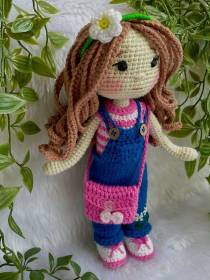 A closer look at the doll in her first outfit. The details on the overalls, like the little embroidered daisies, make her extra special. The clothes are designed to be easy for children to put on and take off.