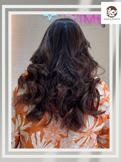 Dark hair with subtle highlights, styled into bouncy curls. This is a great way to add dimension without a drastic color change.