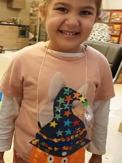 A happy trick-or-treater shows off the pumpkin goody bag she decorated with colorful stars and a friendly smile. Our Halloween workshops are always a favorite.