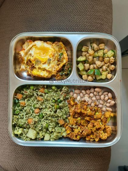 This non-vegetarian meal plate from my subscription features vegetable rice, an egg omelet, boiled peanuts, and roasted cauliflower. It's designed to be balanced, high in fiber, and protein-rich.