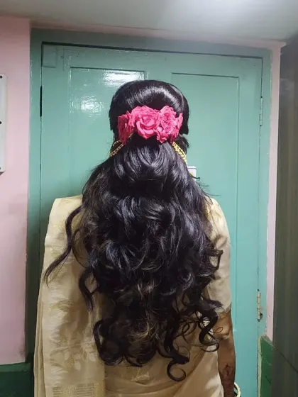 The back view of the reception hairstyle, showing how the curls cascade down, finished with a beautiful floral accessory.