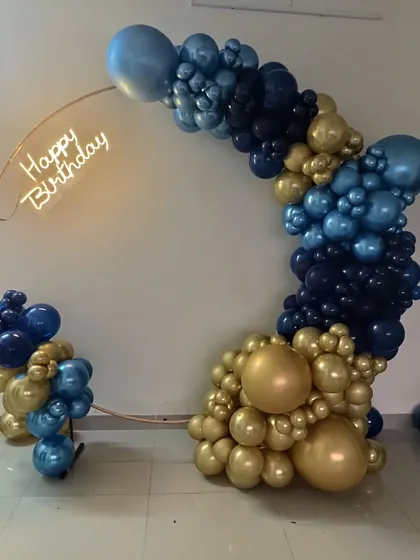 A full view of the navy and gold balloon arch on a copper ring with a neon sign.