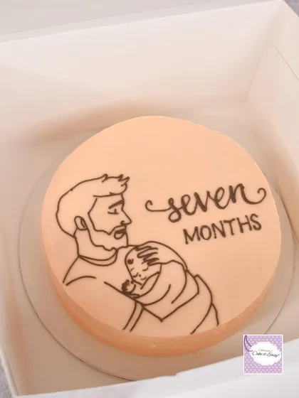 A bento-style cake for a seven-month milestone, featuring a simple line drawing of a father and baby.