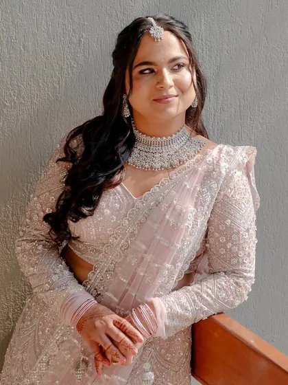 A beautiful outdoor portrait of Madhura in her light pink lehenga. The fresh, rosy makeup complements the soft color of her outfit perfectly.