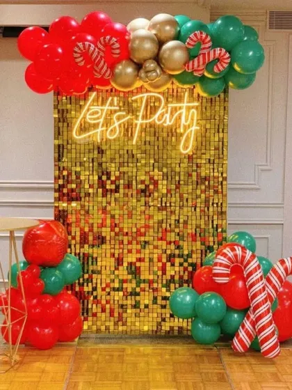 A Christmas-themed take on the popular sequin wall backdrop. I used a gold sequin panel with a 'Let's Party' neon sign, accented with red and green balloons and large candy cane props.