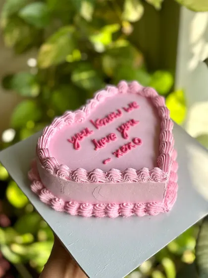 Sweet, simple, and straight to the point. This minimalist pink heart cake features a classic piped border and a simple message, letting the love speak for itself.