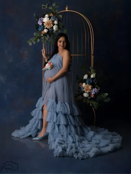 A confident and beautiful pose. The slit in the blue gown adds a touch of glamour, while the cage prop provides a unique and artistic frame.