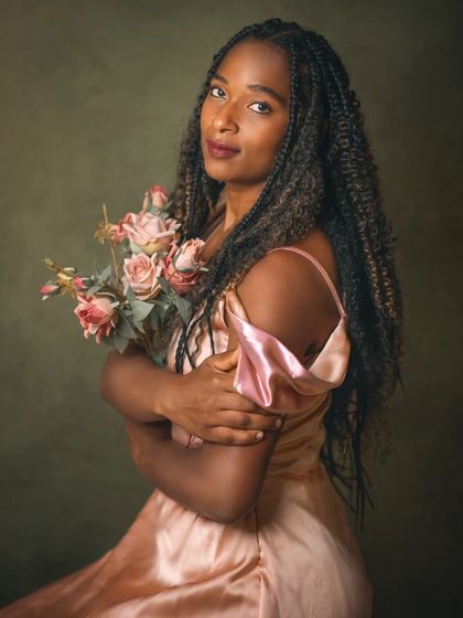 The addition of flowers brings a soft, romantic element to Deborah's portrait. The way she holds the bouquet feels protective and gentle, contrasting beautifully with her strong presence. The lighting enhances the texture of the petals and her satin dress.