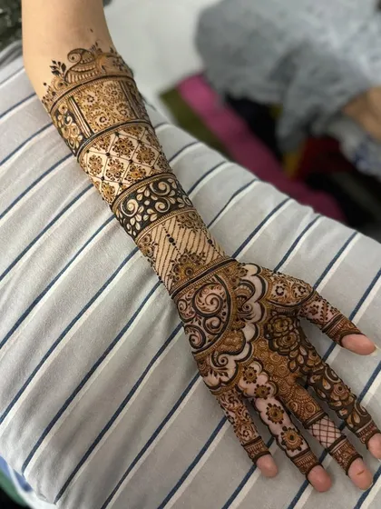 A clear, top-down view of the intricate bridal henna. The design is balanced and covers the hand and arm completely.