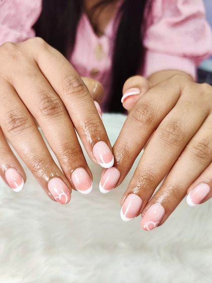 Soft, chic, and timeless. This dreamy pink and white nail art features a subtle ombré base with a classic white French tip and a delicate heart design.