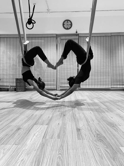 We can only learn to love by loving. This black and white shot captures the connection and symmetry of a partner aerial yoga pose, forming a heart shape.