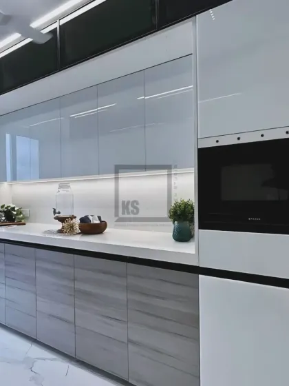 This angle shows the full-height unit with an integrated microwave, a great way to save counter space. The reflective white upper cabinets make the entire kitchen feel brighter and more open.