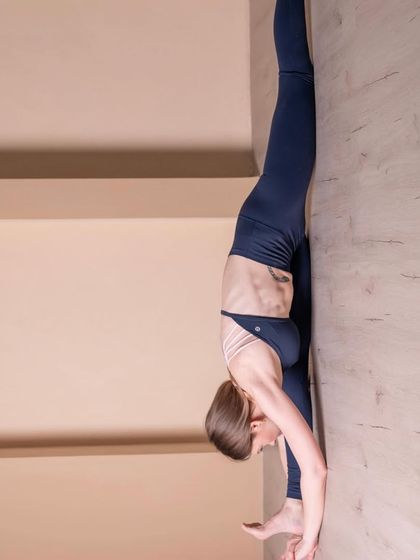 Using a wall to deepen the stretch in a standing split variation. Props can be incredibly helpful for exploring your range of motion safely and building the flexibility needed for more advanced poses.