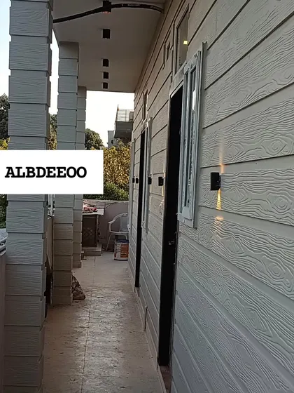 A series of detailed shots of a terrace prefab house's exterior. These images focus on the wood-textured cement plank elevation, modern ceiling lights, and high-quality VEKA window frames.
