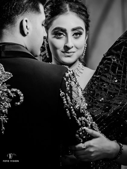 A striking portrait of the bride looking over the groom's shoulder, her gaze direct and captivating in this black and white shot.