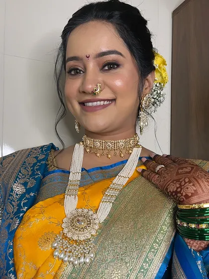 A radiant Maharashtrian bride on her wedding day, showcasing a classic yellow and blue saree combination.