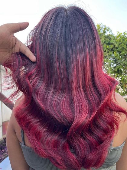This vibrant red look is designed to turn heads. The color is rich and fiery, with different tones of red creating dimension and movement throughout the hair.