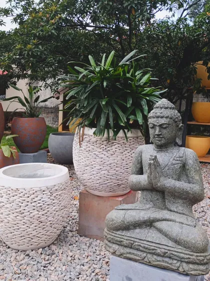 Our meditating Buddha statue in natural stone, paired with our unique Balinese pebble planters. This combination of textures creates a grounded, earthy aesthetic perfect for any garden.