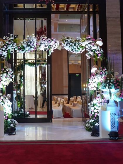 This entrance features a beautiful blend of pink and white florals, creating a soft and romantic archway. The design is perfect for a daytime or evening event, offering a classic and welcoming floral greeting.