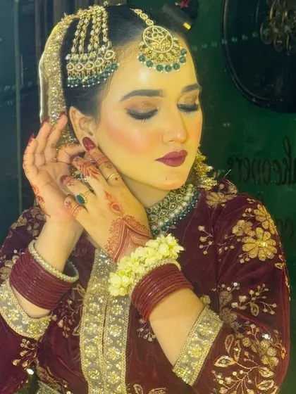 A beautiful candid moment of a Nikkah bride. Her makeup features a soft, dewy base with a hint of blush, paired with a deep maroon lip and smoky eyes, perfectly complementing her velvet outfit.