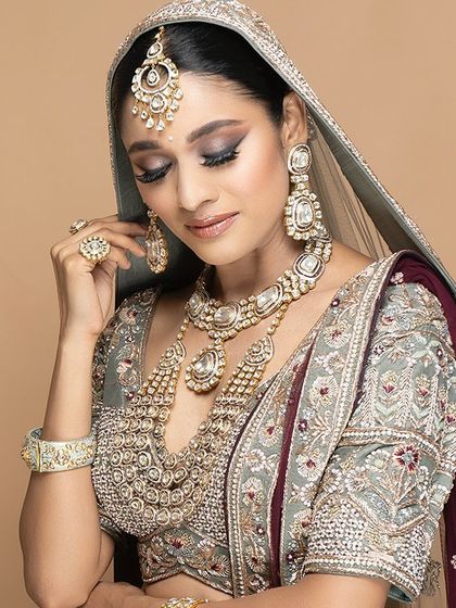 A full bridal look, perfected with our custom tailoring. This sage green and maroon lehenga is adorned with heavy jewellery, showing how we can help style a complete, regal ensemble for your wedding day.