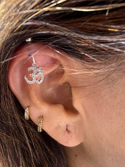 A simple yet powerful stack with a sparkling Om charm in the helix, paired with two small gold hoops. Perfect for a spiritual and stylish statement.