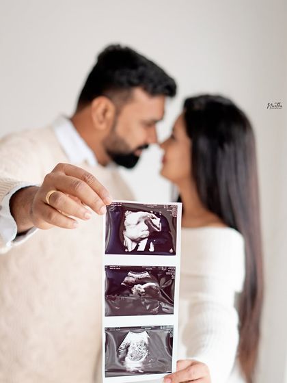 A creative maternity announcement photo, with the couple holding up their ultrasound pictures.