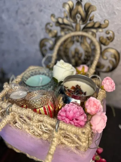 A cute and festive jute basket hamper for Diwali. It's filled with a matki candle, a crystal candle, tea light holders, chocolates, and savories, all open for customization.