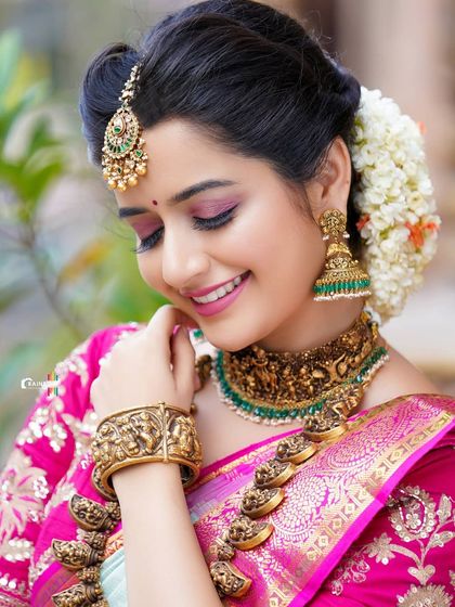 A joyful, candid shot of Ashika Ranganath, capturing her bright smile and the elegance of her traditional look.