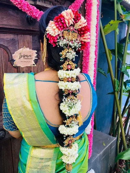 An intricate traditional South Indian bridal hairstyle. This classic braid is heavily adorned with fresh flowers and traditional 'jade billai' hair ornaments, creating a truly regal look for the main wedding ceremony.