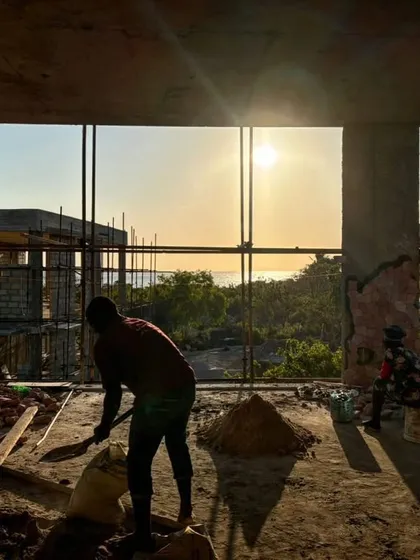 Workers are silhouetted against the setting sun over the ocean at our Zanzibar site. The construction process is timed to the rhythm of the day, with the views providing constant inspiration.