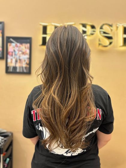 A beautiful back view of a long balayage hairstyle. The hand-painted technique creates a natural, sun-kissed effect that adds dimension and shine.