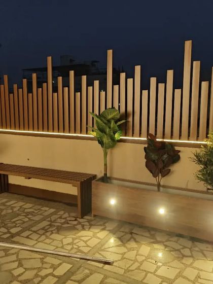 A custom-built privacy wall made of wooden slats of varying heights, with an integrated planter and bench.