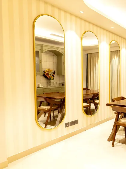 To create an illusion of spaciousness in the dining area, we installed a series of vertical, gold-rimmed mirrors. They reflect light and the room's elegant details, while the subtle striped wallpaper adds another layer of texture.