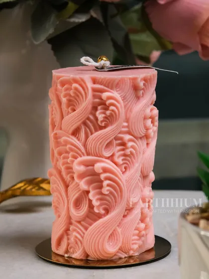 An intricately carved pink pillar candle that adds texture and a pop of color. The details on this piece are all poured and finished by hand.