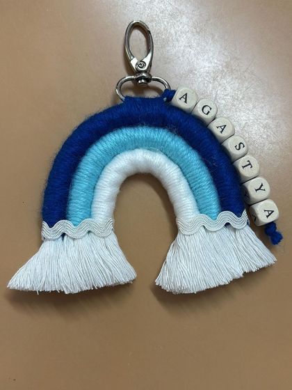 A personalized rainbow keychain in shades of blue for "Agastya". A perfect little gift for a baby boy.
