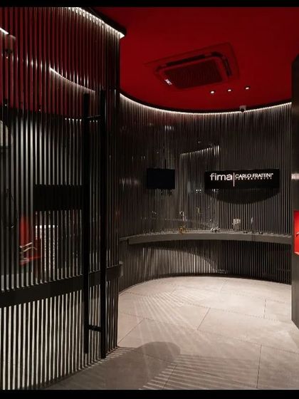 Another perspective of the Fima studio, highlighting how the curved architectural elements are accentuated with light. The design uses darkness as a canvas, with light carefully painted on to guide the eye and feature the displayed products in an artistic, gallery-like setting.