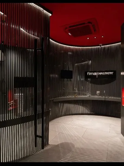 Another perspective of the Fima studio, highlighting how the curved architectural elements are accentuated with light. The design uses darkness as a canvas, with light carefully painted on to guide the eye and feature the displayed products in an artistic, gallery-like setting.
