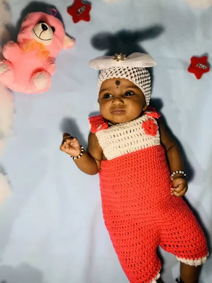 A two-tone romper in red and white, as seen on a happy little client. This style is similar to overalls and is a playful and cute option for a baby's wardrobe.