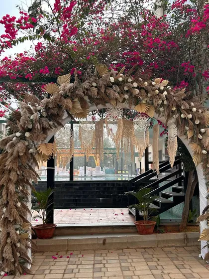 A beautiful boho-themed entrance arch using dried pampas grass, macrame hangings, and white florals for a soft, rustic, and chic look.