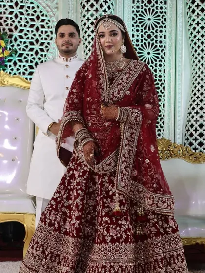 A regal portrait of the bride in her stunning red lehenga, with the groom standing proudly by her side.