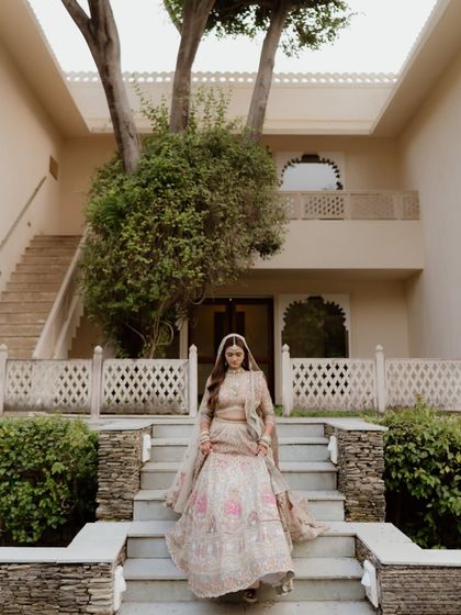 The bride descending a grand stone staircase, her elaborate lehenga spread out beautifully. This shot captures a moment of regal elegance and poise.