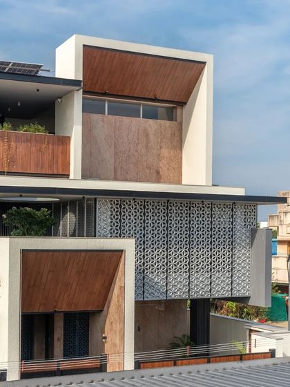 The facade is a complex composition of solids and voids, textures and smooth surfaces, demonstrating a sophisticated approach to residential design.