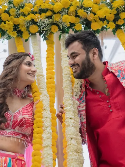 A candid close-up of the couple sharing a laugh between garlands of marigolds at their Haldi ceremony.