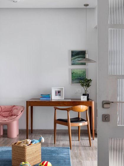 A study corner within a child's room. The simple wooden desk and chair provide a dedicated space for creativity and learning, while the fun pink sculptural chair adds a touch of playful design.
