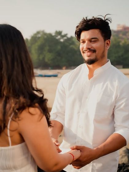 The groom looks at his bride-to-be with a loving smile. This candid shot captures his adoration and the happy, relaxed atmosphere of their beach pre-wedding shoot.