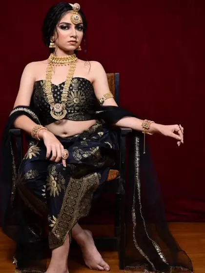 A regal pose in the black and gold dhoti-saree, paired with heavy gold temple jewellery. This look combines tradition with a modern, edgy silhouette.