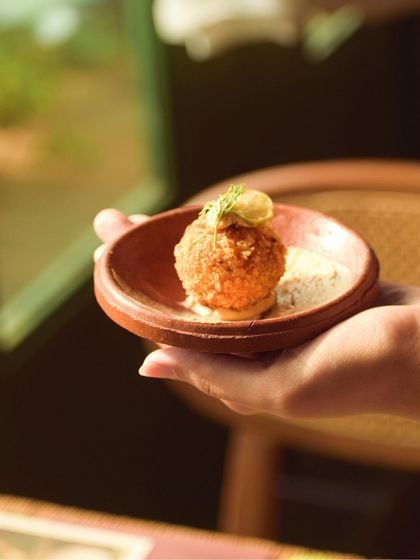 A delicate croquette, held in hand, from 'The Wonder Years' pop-up. A perfect, single bite of Goan-inspired flavor.