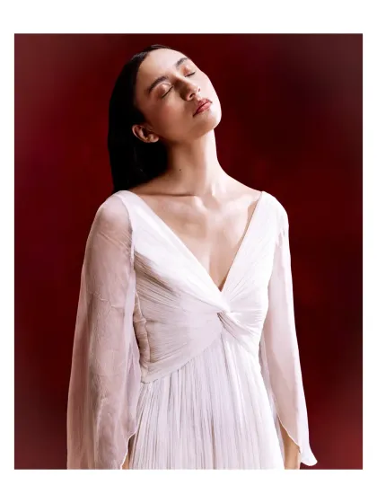 A study in quiet elegance, this white dress features a draped V-neckline and flowing bell sleeves. The soft, ethereal fabric makes it a beautifully understated choice for any special occasion.