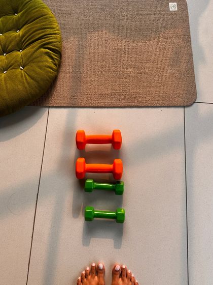 A view from the mat, showing a set of colorful dumbbells ready for a yoga with weights session.